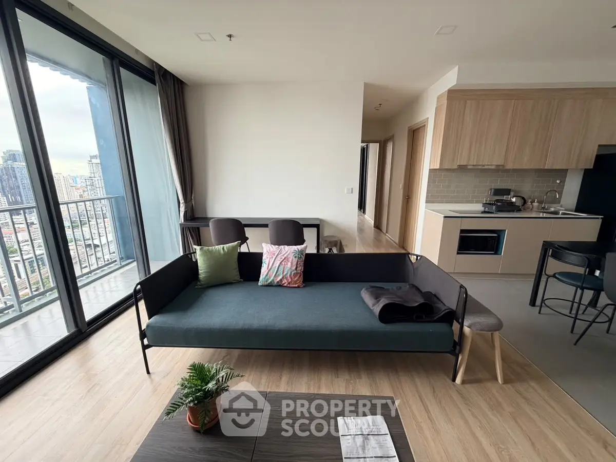 Modern living room with open kitchen and city view balcony in stylish apartment.