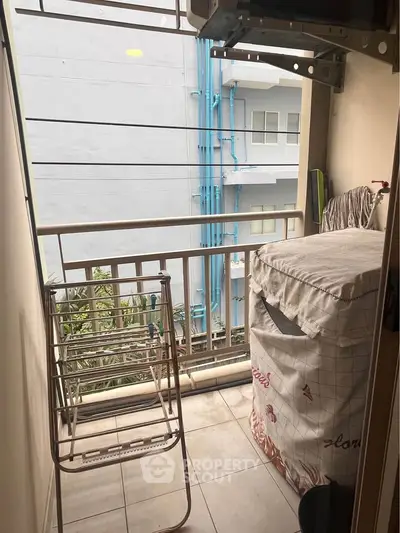 Compact balcony with laundry area and city view, ideal for urban living.