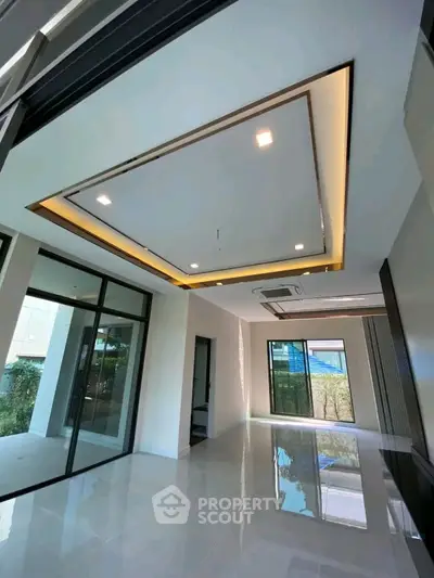Modern interior with sleek ceiling design and large windows offering natural light.