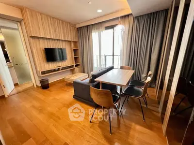 Modern living room with wooden flooring, stylish furniture, and a wall-mounted TV.