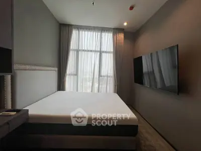 Modern bedroom with large window and wall-mounted TV in a stylish apartment.