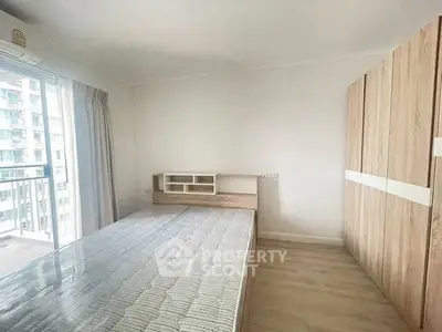 Spacious bedroom with modern furniture and balcony view in high-rise apartment