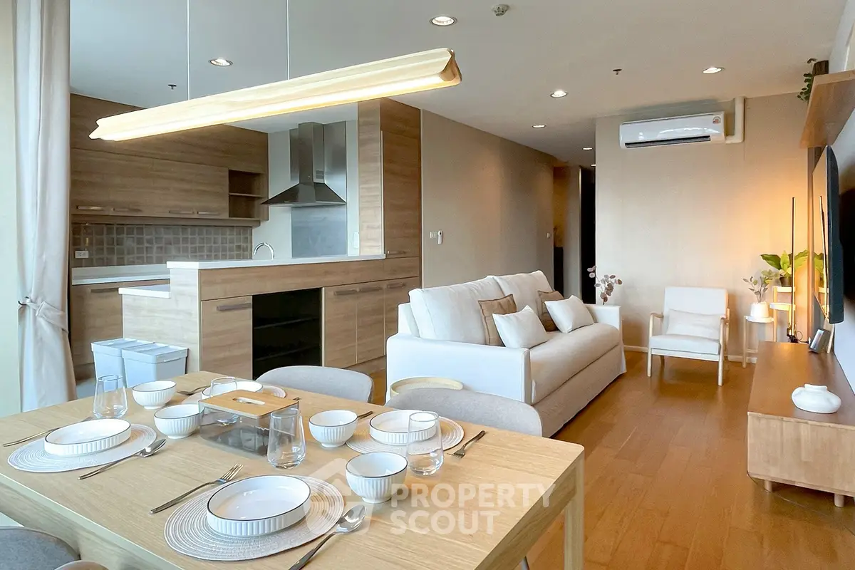 Modern open-plan living room and kitchen with elegant wooden finishes and cozy dining area.