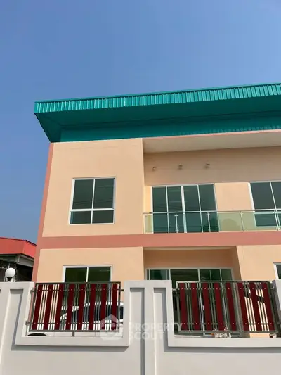 Modern two-story building with colorful facade and large windows under clear blue sky.