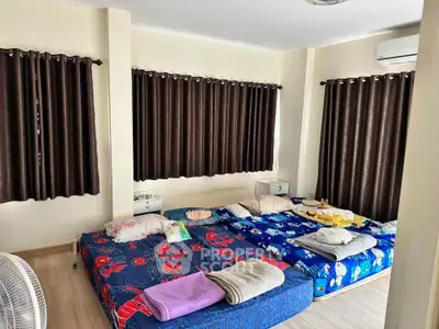 Spacious bedroom with multiple beds and dark curtains, ideal for shared living.