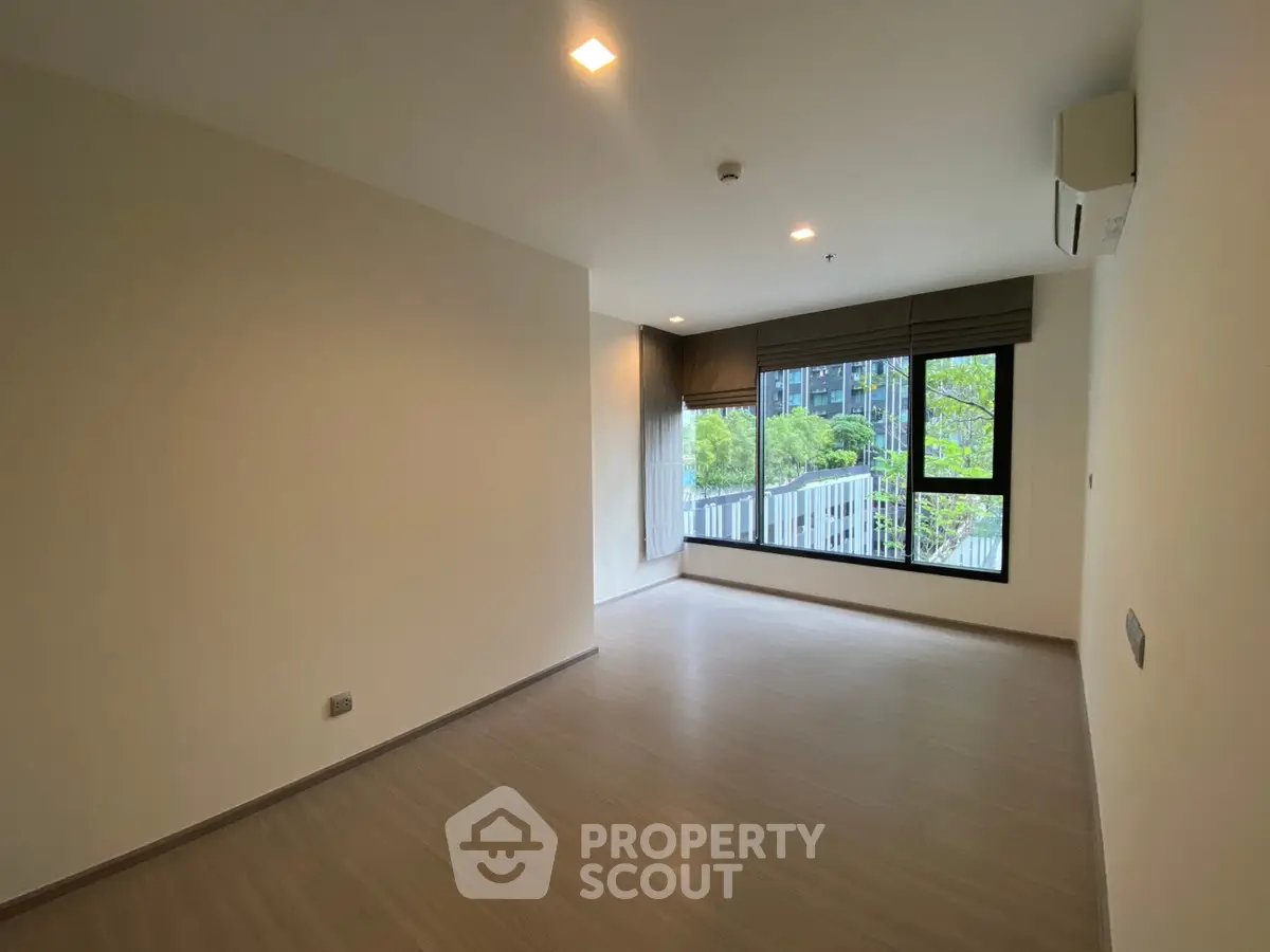 Spacious modern living room with large window and wooden flooring