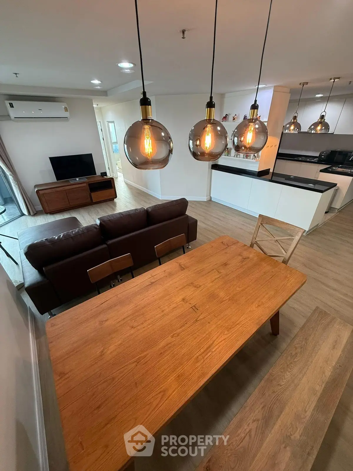 Modern open-plan living room with stylish lighting and sleek kitchen design