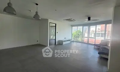 Spacious modern living room with large windows and minimalist design in a high-rise apartment.