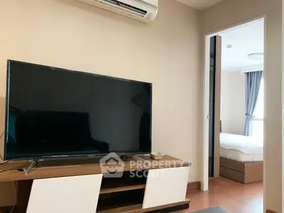 Modern living room with sleek TV and cozy bedroom view in stylish apartment.