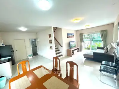 Spacious living room with dining area and modern decor, featuring large windows and natural light.