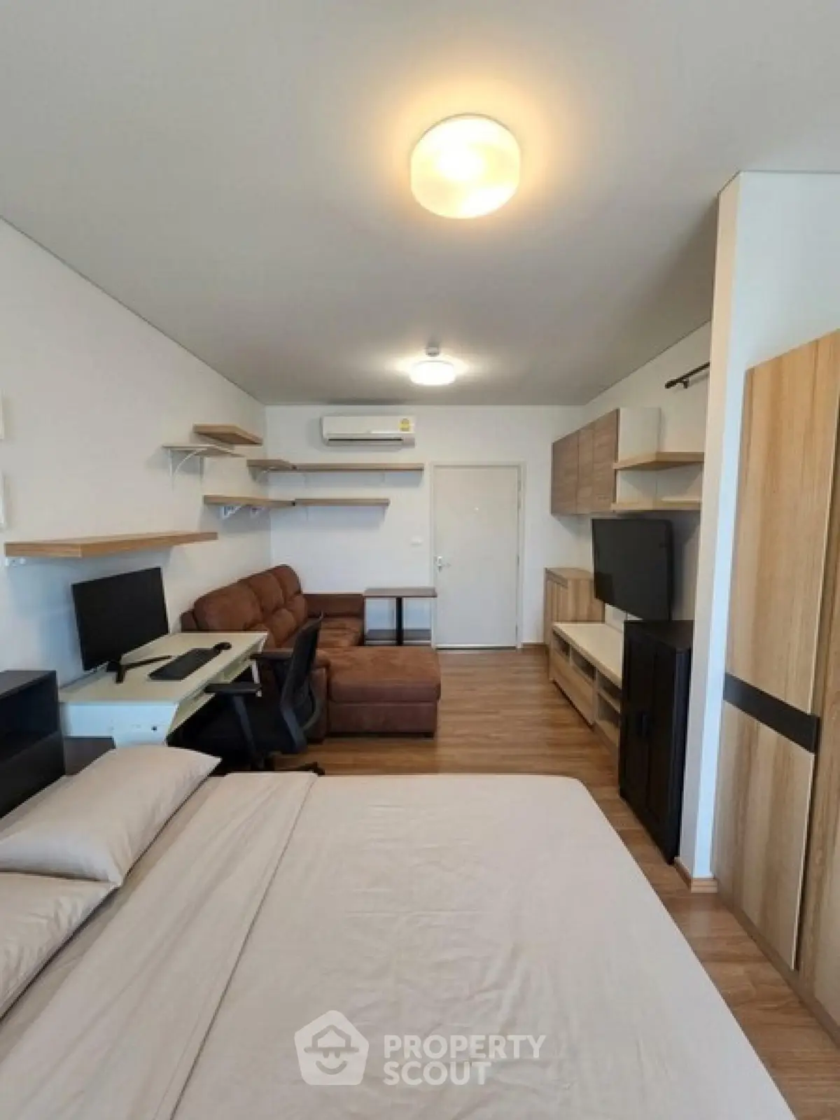 Modern studio apartment with cozy living area and workspace, featuring sleek furniture and warm lighting.