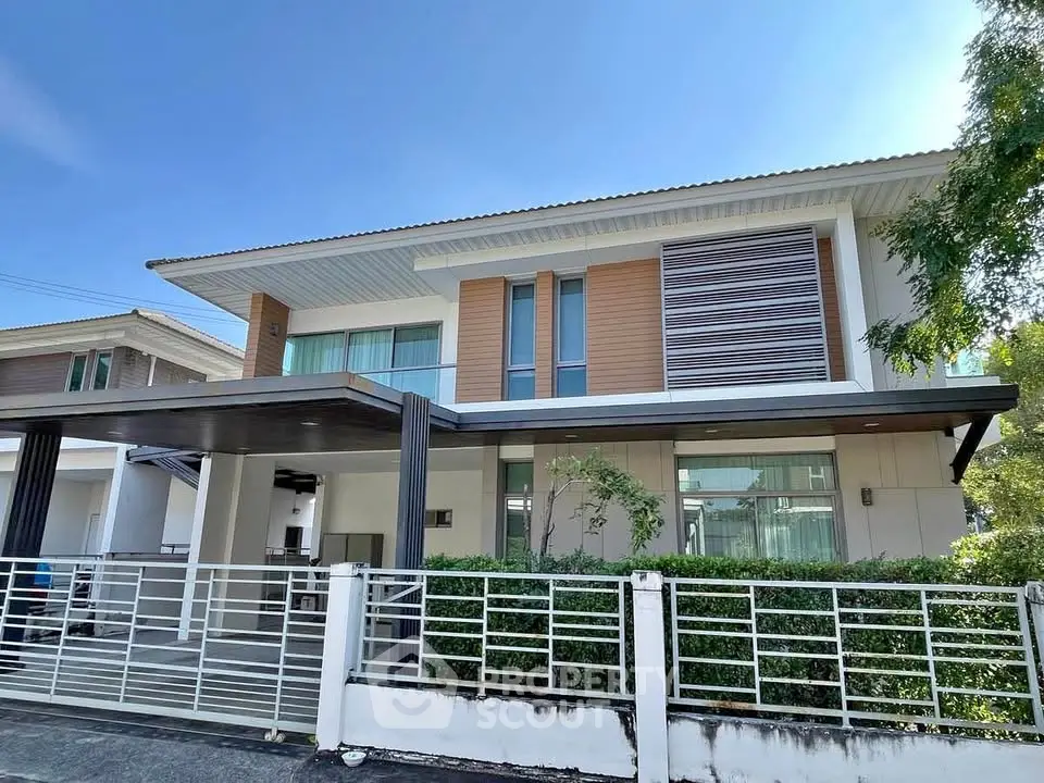 Modern two-story house with sleek design and spacious balcony, featuring a stylish facade and lush greenery.