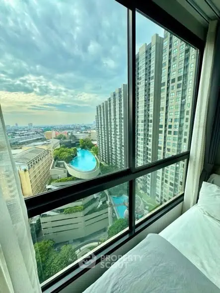 Stunning high-rise view with pool and cityscape from modern apartment window.