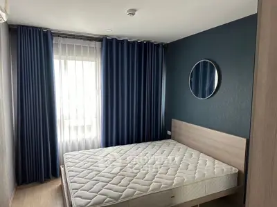 Modern bedroom with stylish blue curtains and round mirror, featuring a comfortable mattress.