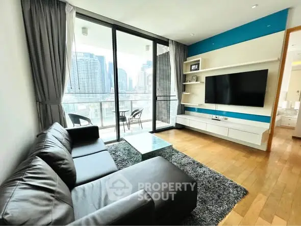 Modern living room with city view, featuring sleek black sofa, glass coffee table, and wall-mounted TV.