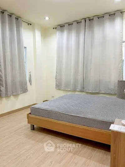 Spacious bedroom with modern design and ample natural light, featuring a comfortable bed and elegant curtains.