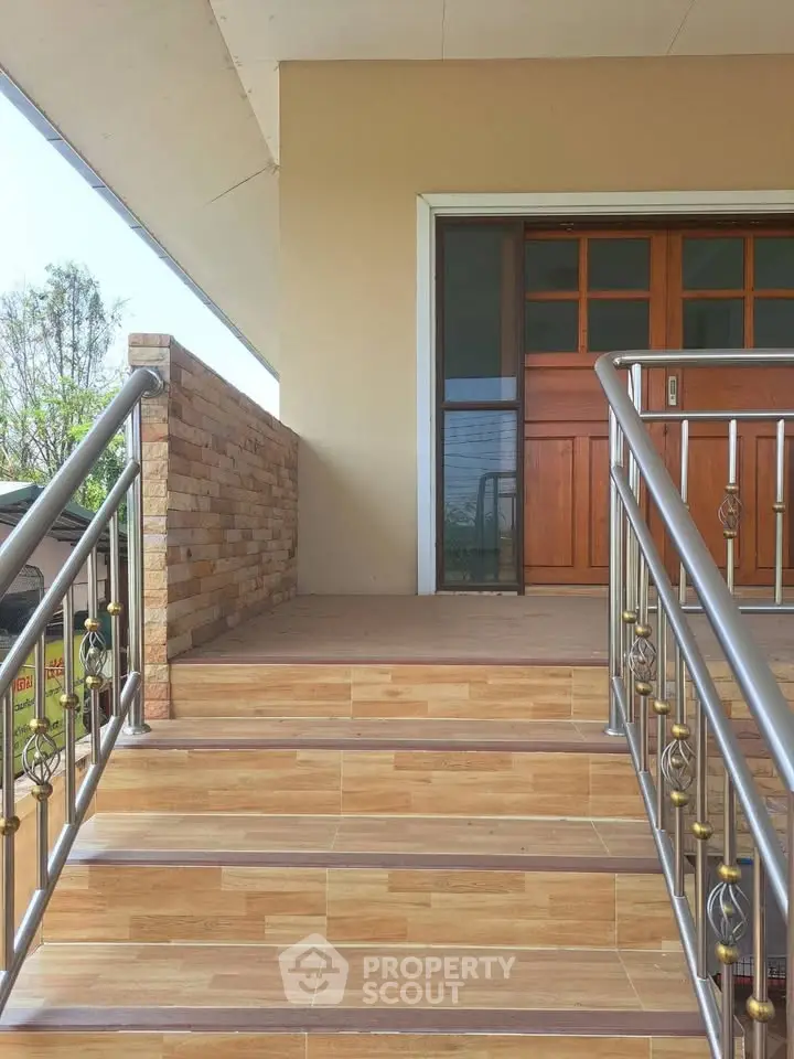 Elegant entrance with wooden door and stylish railing, perfect for welcoming guests.