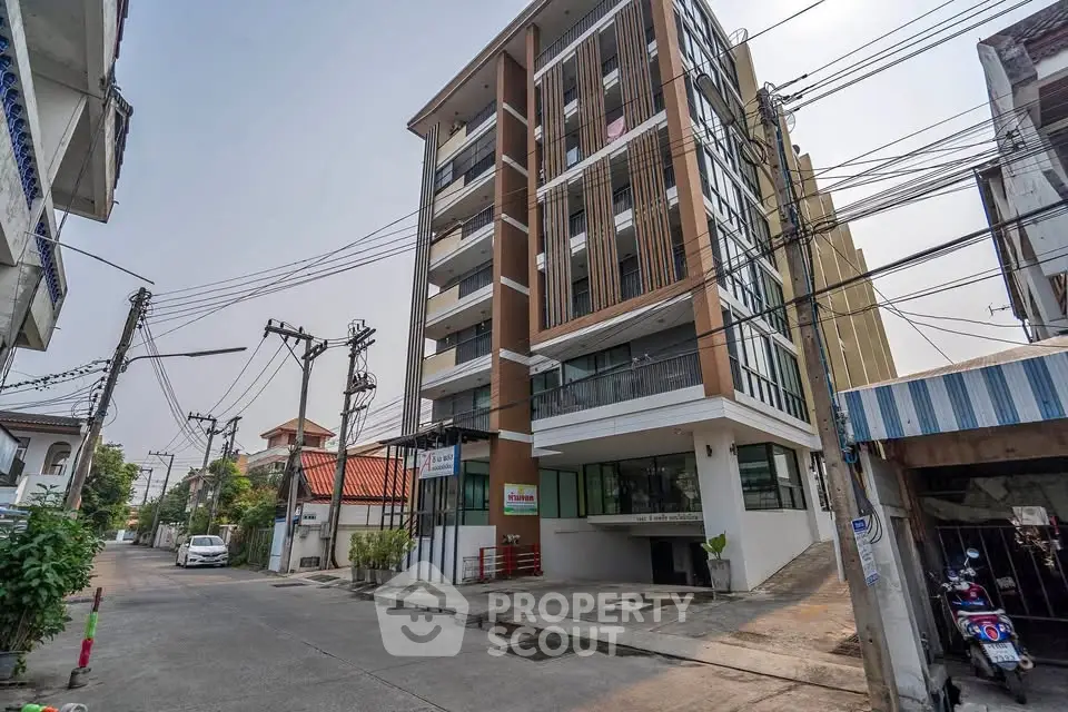 Modern multi-story apartment building on a quiet street with contemporary design and ample balconies.