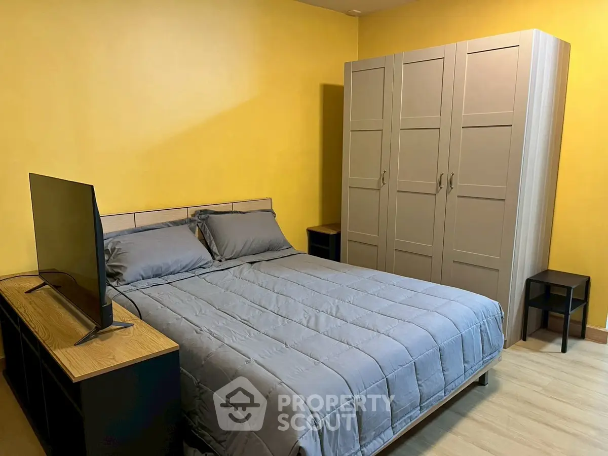 Cozy bedroom with modern furniture and vibrant yellow walls, perfect for relaxation.
