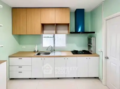 Modern kitchen with sleek cabinetry and gas stove in a bright, mint green setting.