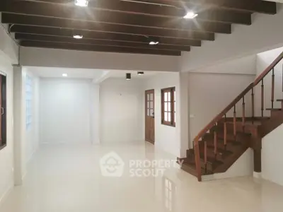 Spacious open-plan living area with elegant wooden staircase and modern lighting.