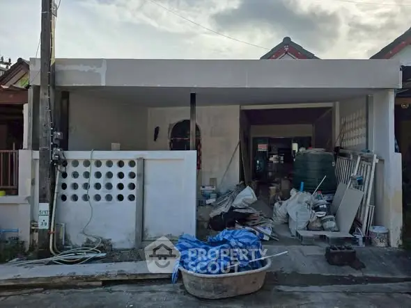 Under-construction house exterior with building materials and tools scattered around.