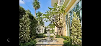 Elegant garden with fountain and lush greenery beside a luxurious building