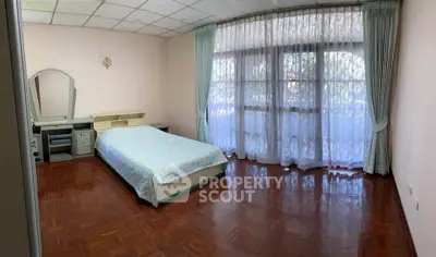 Spacious bedroom with large window and parquet flooring