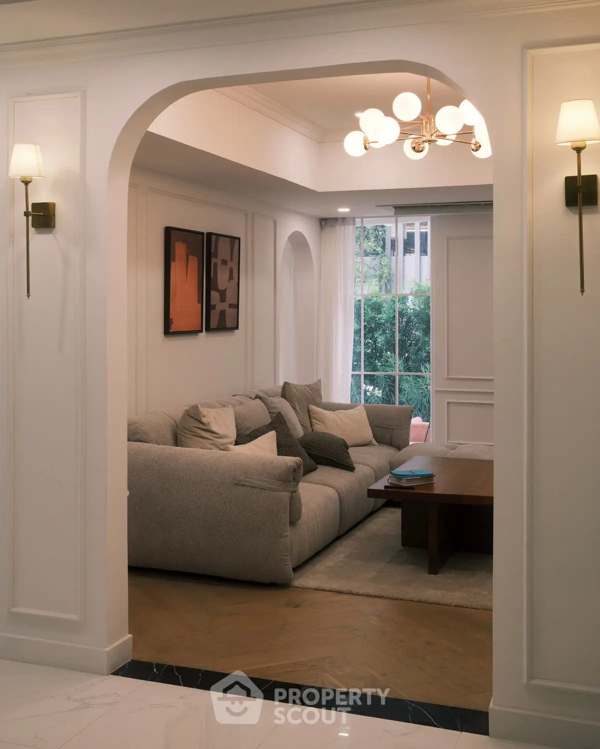 Elegant living room with plush sofa, stylish lighting, and large window overlooking greenery.