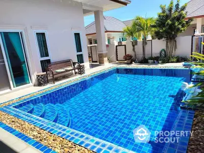 Luxurious villa with private blue-tiled swimming pool and lush garden.