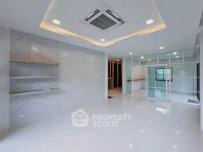 Modern living room with sleek design and built-in shelves, featuring recessed lighting and large windows.