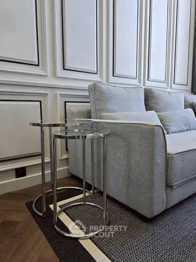 Elegant living room with modern gray sofa and stylish side tables on a chic rug.