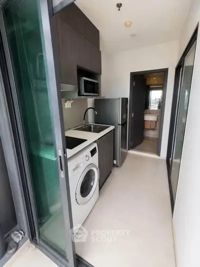 Compact kitchen with washing machine and modern appliances in sleek apartment