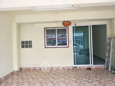 Spacious tiled patio with sliding glass doors and window, ideal for outdoor relaxation.