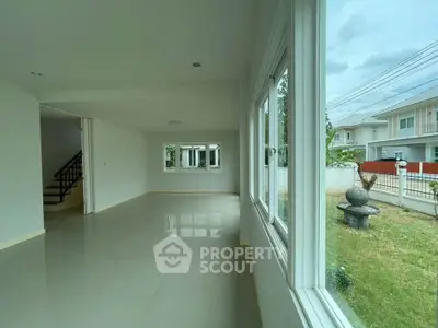 Spacious living room with large windows offering natural light and garden view in modern home.