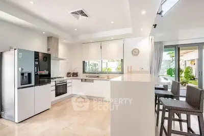 Modern kitchen with sleek appliances and open layout, featuring a breakfast bar and garden view.