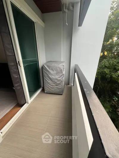 Charming balcony with sliding glass door and lush greenery view, perfect for relaxation and fresh air.