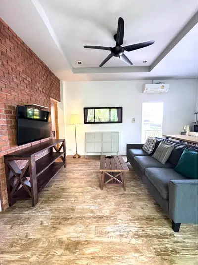 Stylish living room with brick accent wall, modern furniture, and ceiling fan in a cozy home.