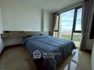 Spacious bedroom with large windows offering stunning city views, perfect for relaxation and comfort.