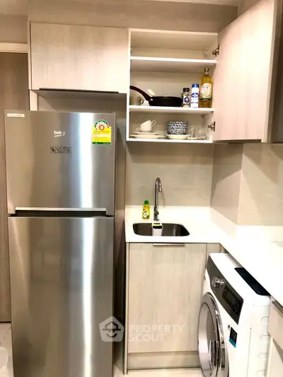 Modern kitchen with stainless steel fridge and washing machine in compact layout.