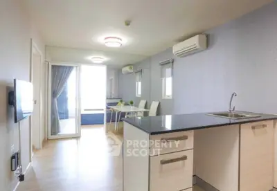Modern open-plan living area with sleek kitchen and dining space, featuring air conditioning and natural light.