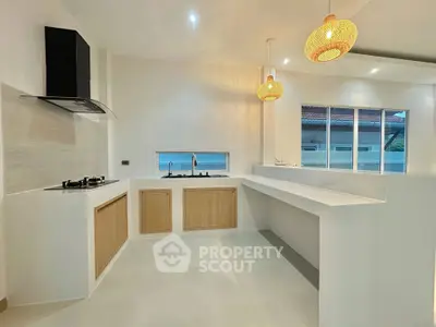 Modern kitchen with open layout and gas stove, featuring sleek countertops and stylish pendant lighting.