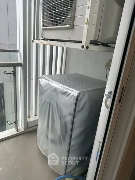 Compact balcony with washing machine and air conditioning unit in modern apartment.