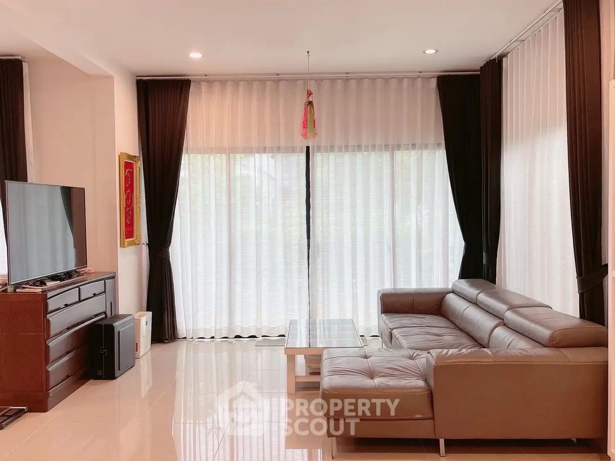 Spacious living room with modern leather sofa and large TV, perfect for relaxation.