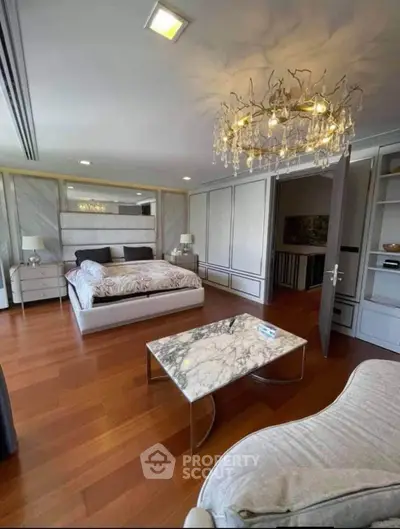 Luxurious bedroom with elegant chandelier and marble accents, featuring spacious layout and stylish furnishings.