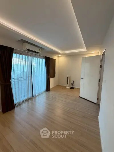 Spacious modern living room with wooden flooring and large windows in a stylish apartment.