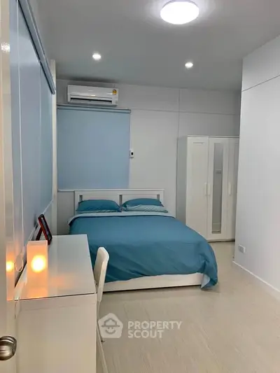 Modern bedroom with blue bedding, sleek white furniture, and ambient lighting.