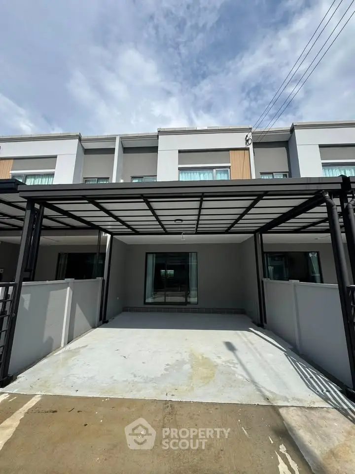 Modern townhouse exterior with spacious driveway and sleek design under a clear blue sky.