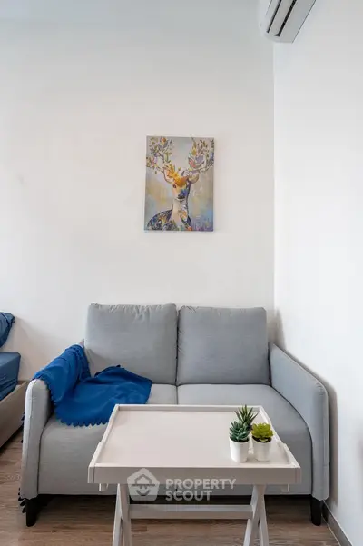 Cozy living room with modern sofa, stylish decor, and air conditioning, perfect for relaxation.
