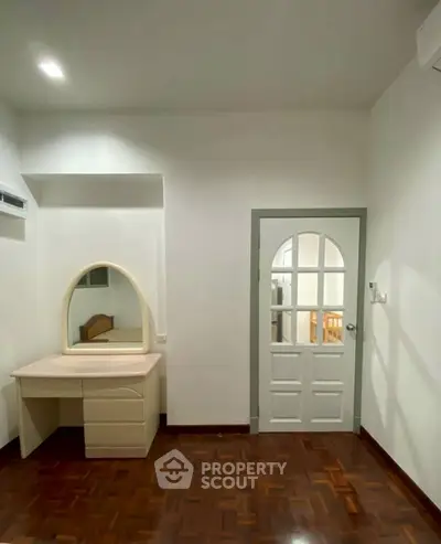 Spacious bedroom with parquet flooring and elegant vanity desk